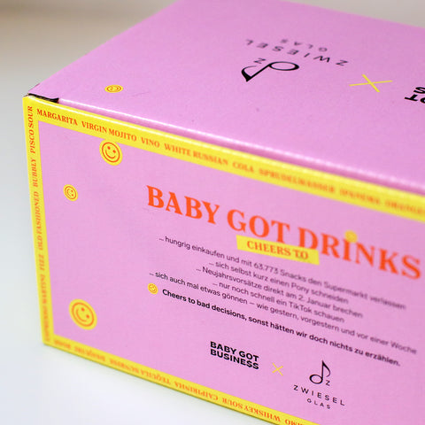 Seitenansicht der Gläser-Box mit auffälligem, großem orangenem Schriftzug „Cheers to poor decisions“ auf pinkem Untergrund, verziert mit gelben Smileys.